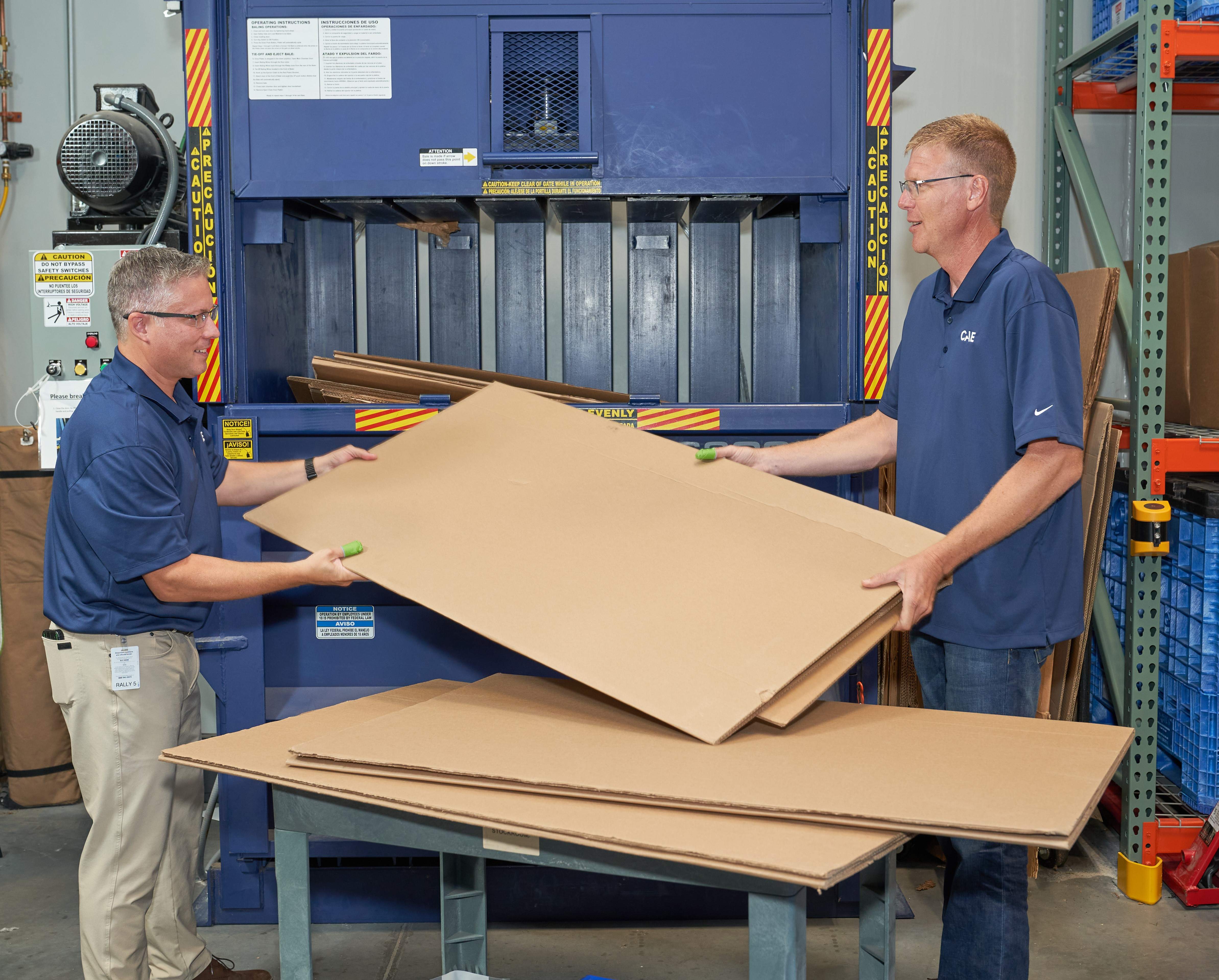 CAE Healthcare employees load boxes into an on-site baler for more efficient recycling.